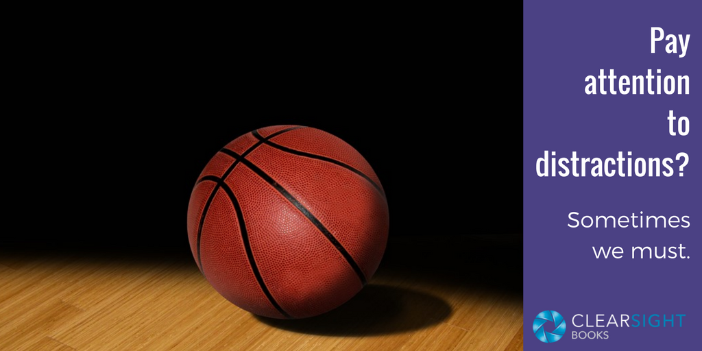 image of basketball on darkened court floor with words: Pay attention to distractions? Sometimes we must.